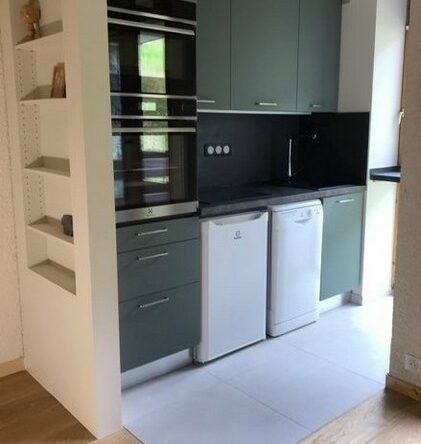 Cuisine Montchavin La Plagne meubles XL façades vert gris 22 mm en résine, lavables hydrofuges, caisson anthracite en métal. Crédence céramique noire et plinthes facile d'entretien